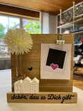 Dekorativer Holzrahmen mit Blumenglas, Blume und einem Polaroid Foto als creative Gestaltung und Darstellung von Fotos